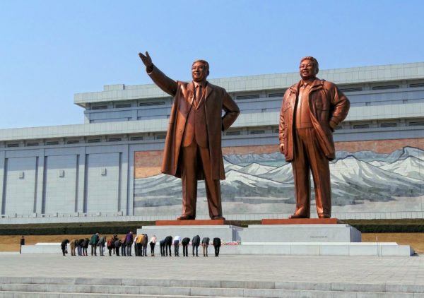 Group of people bowing in front of the statues of Kim Il-sung and Kim Jong-il at the Mansudae Grand Monument