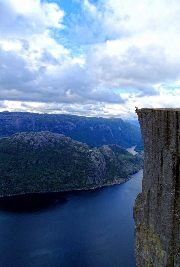 Photo of man contemplating the fragility of life while sitting on the edge of Preikestolen / Pulpit Rock, Norway.