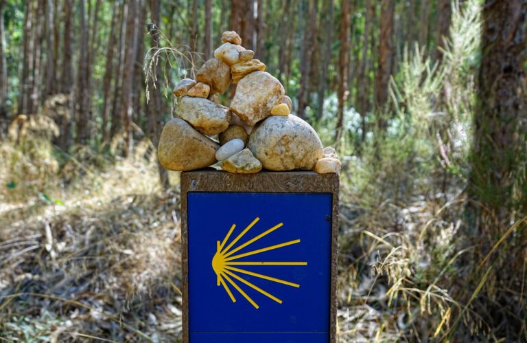Photo of typical stones piled on top of a sign showing the way on Camino de Santiago.