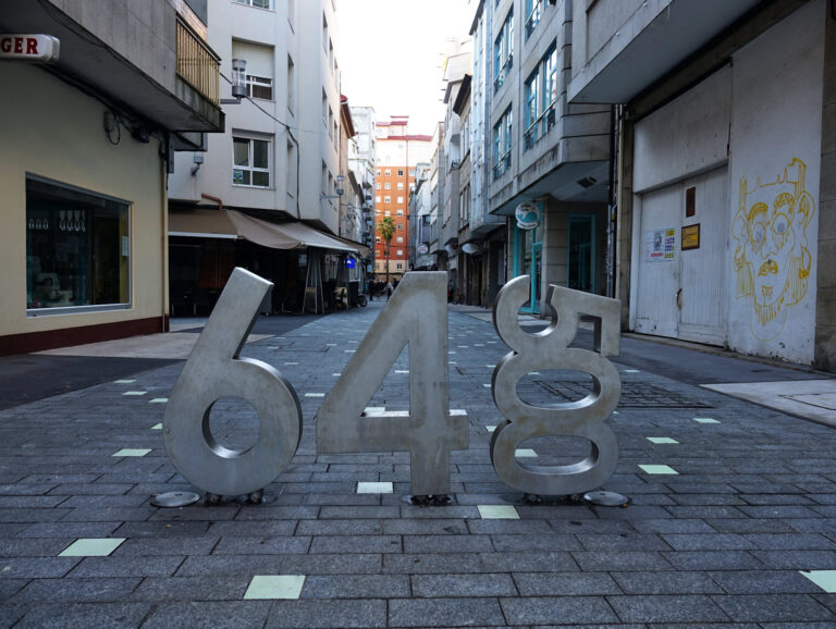 Photo of distance marker for the Camino de Santiago in the middle of a pedestrian street in Pontevedra, Spain.