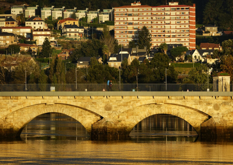 Photo of pilgrim walking across a bridge in Pontevedra, Spain.