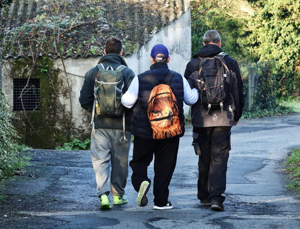 Photo of three men supporting each other to complete the Camino de Santiago.